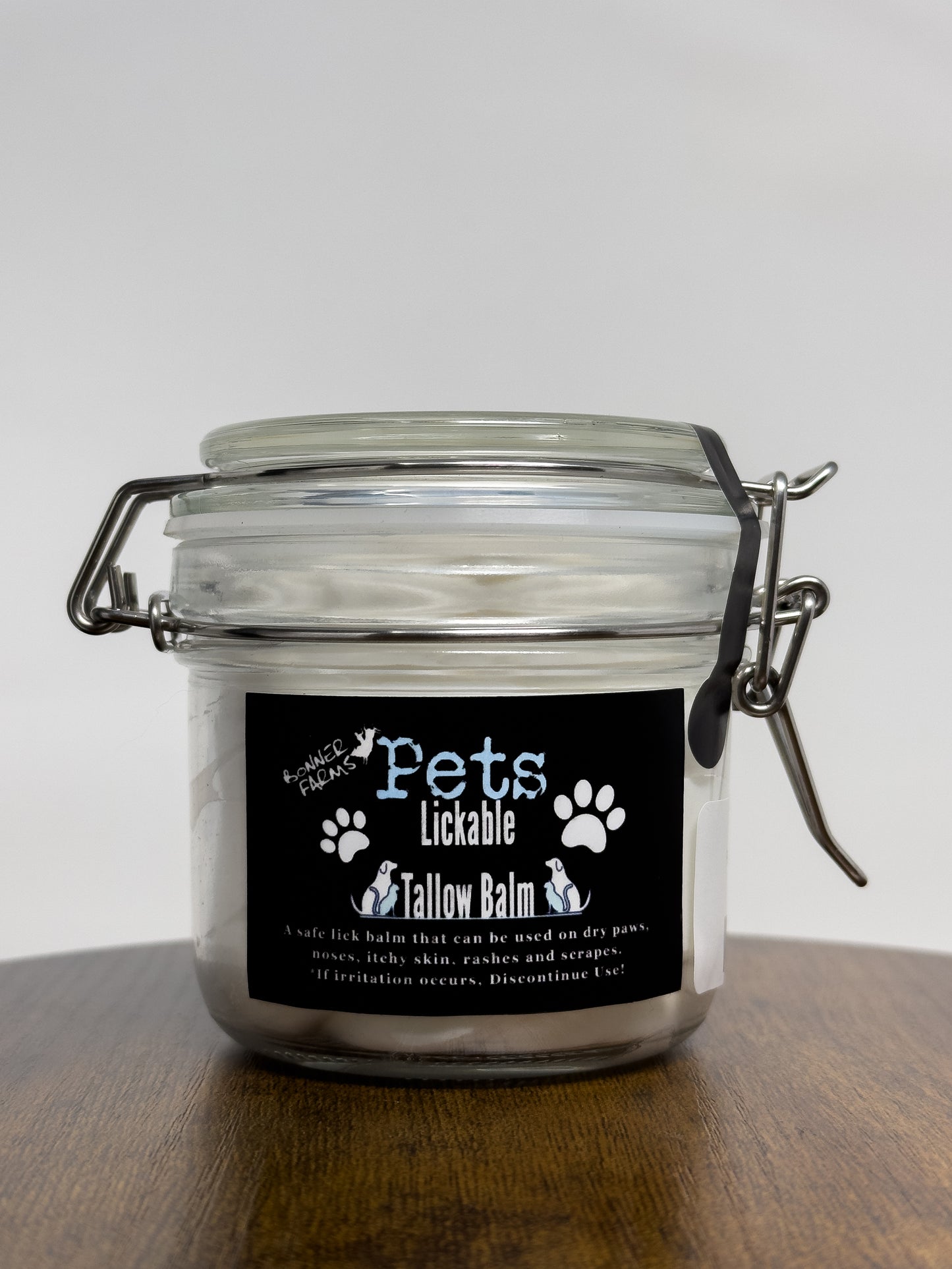 Jar of tallow balm for pets with a label on a wooden surface
