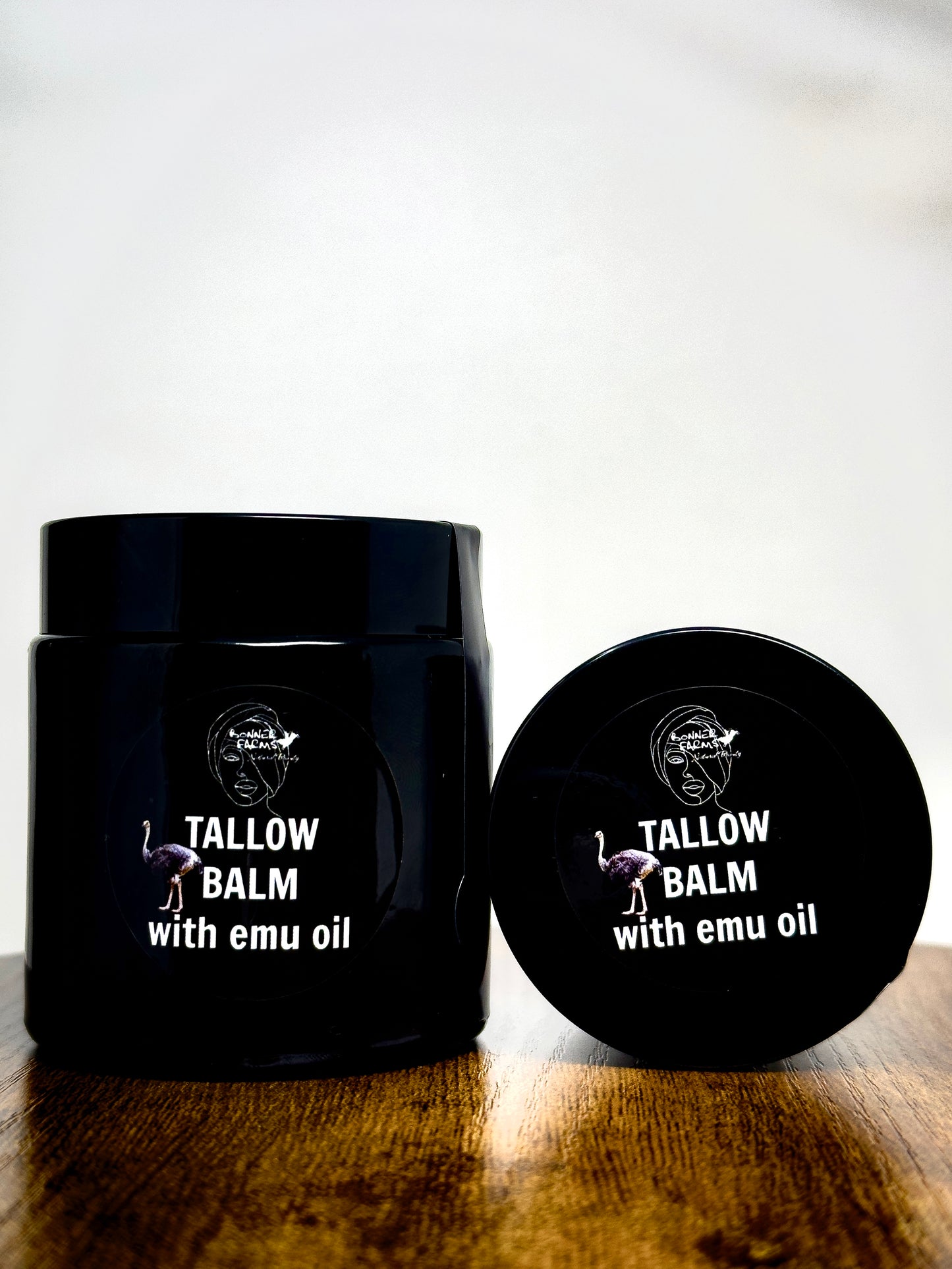Black jar and lid of tallow balm with emu oil on a wooden surface